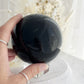 BLACK OBSIDIAN SPHERE. APPROX 9.5 CM. STONED AND SAGED AUSTRALIA.