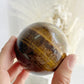 TIGERS EYE SPHERE APPROX 6.4CM. STONED AND SAGED AUSTRALIA.