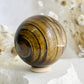 TIGERS EYE SPHERE APPROX 6.1CM. STONED AND SAGED AUSTRALIA.