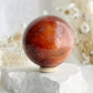 CARNELIAN SPHERE APPROX 6.1CM. STONED AND SAGED AUSTRALIA.